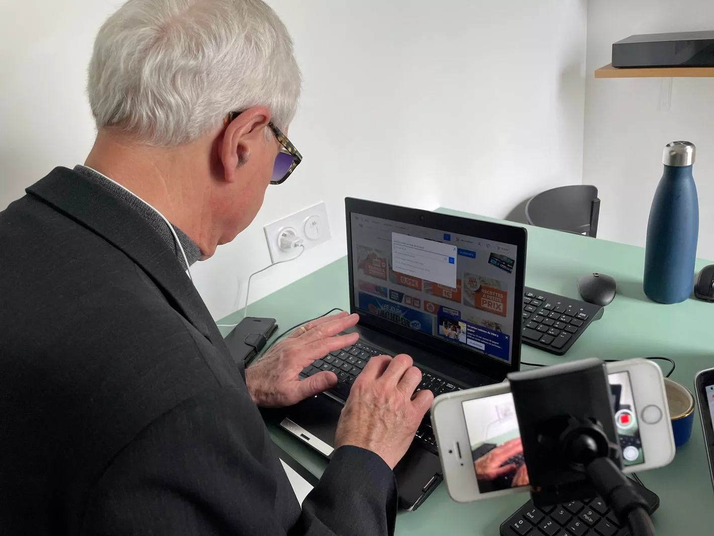 Personne malvoyante testant une interface web sur un ordinateur. Sa navigation est filmée par un téléphone grâce à un trépied.